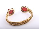 a gold cuff bracelet with red stones and diamonds