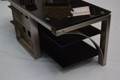 une table en verre avec un plateau noir posé sur un socle blanc