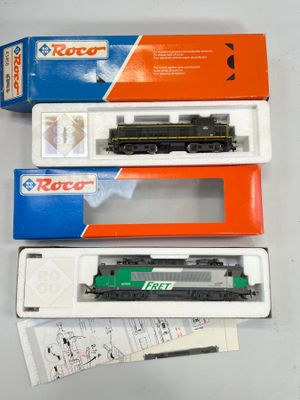 trois trains miniatures dans leurs boîtes, posés sur une table blanche