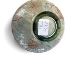 a green vase with writing on it sitting on a white surface