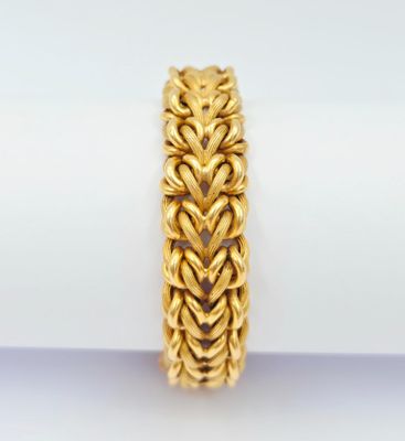 un gros plan d'un bracelet en or posé sur une serviette