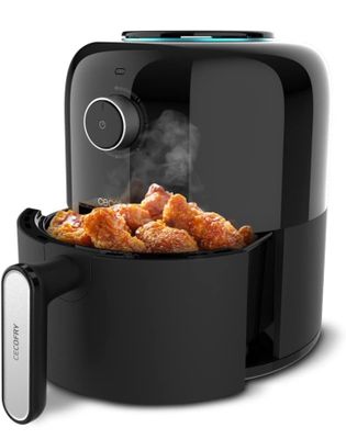 a black air fryer filled with fried chicken sitting on top of a counter