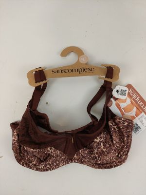 un soutien-gorge marron et blanc orné d'un nœud marron, suspendu à un cintre en bois