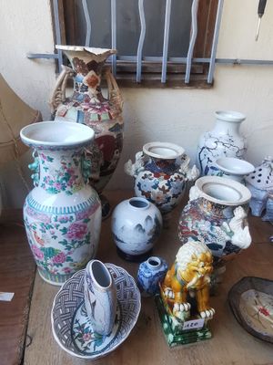 de nombreux vases de toutes sortes posés sur une table, avec une fenêtre en arrière-plan