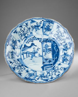 a blue and white plate with a design of a woman in a garden