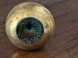 a gold vase on a wooden table with a blue eye