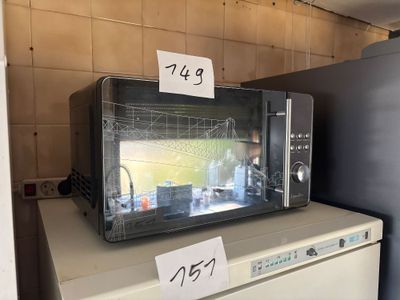 a microwave sitting on top of a refrigerator in a kitchen
