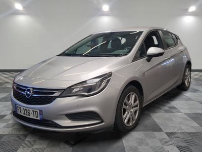 une voiture argentée est garée dans une pièce au sol en damier