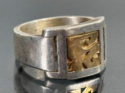a silver ring with a gold design on it