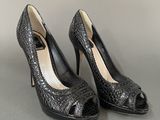 pair of women ' s black high heeled shoes on a gray surface