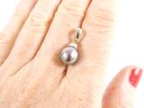 a woman ' s hand holding a ring with a pearl on it