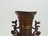 a bronze vase with a bird and flower design on it