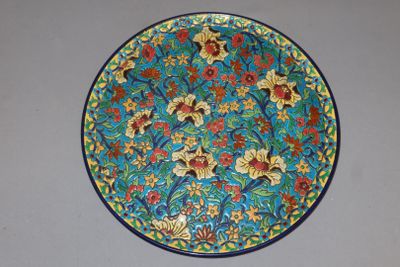 une assiette bleue et jaune décorée de fleurs et de feuilles