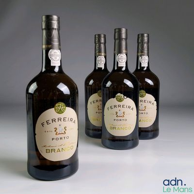 quatre bouteilles de vin sont alignées sur une surface blanche