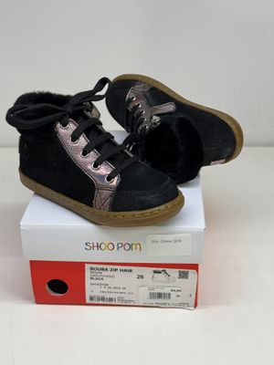 une paire de chaussures noires et roses posée sur une boîte blanche