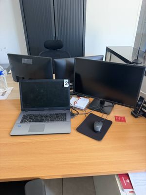 un bureau sur lequel se trouvent trois ordinateurs et une souris