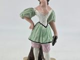 a figurine of a woman in a green dress and hat