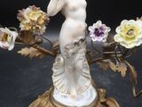 une statue représentant une femme tenant des fleurs, posée sur une table