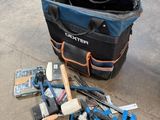 un sac rempli d'outils posé par terre à côté d'une valise