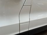 the side of a white car with a cracked door and a crack in the side of it