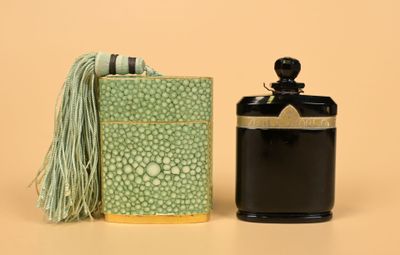 a bottle of perfume next to a box with a tassel on it