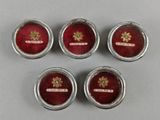 four silver and red buttons with a gold emblem on them