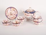a tea set with a teapot, cups, saucer, and spoons