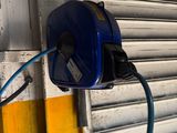 un tuyau bleu fixé au mur à côté de la porte de garage