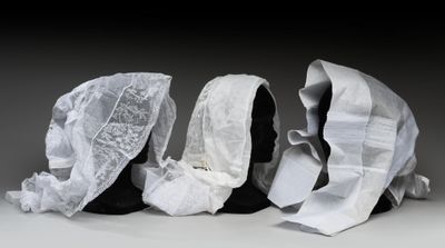 trois mannequins noirs dont la tête est recouverte d'un tissu blanc