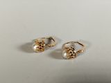a pair of gold and pearl earrings on a white surface