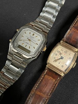 two watches sitting next to each other on a black surface
