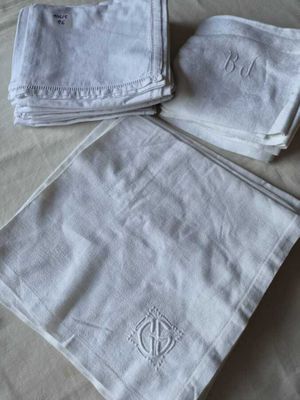 trois serviettes blanches ornées de monogrammes sont posées sur un lit