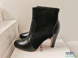 black leather ankle boots with wooden heel on display in front of a white box