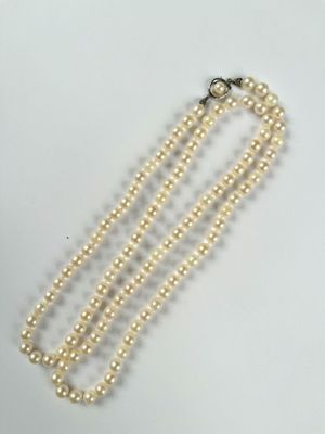 a close up of a white pearl necklace on a white surface