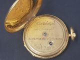 a gold pocket watch sitting on a blue surface