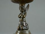 an antique bronze cup with an angel holding a bird on it
