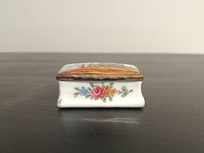 a small white box with flowers on it on a table