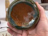 a person holding a brown and green bowl in their hand