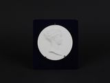 a white medallion with a woman ' s head in profile on a black surface