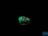 an image of a green stone in the dark on a black surface