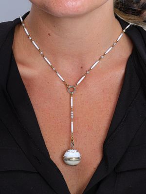 Cette femme porte un t-shirt noir et un collier orné d'une perle blanche.