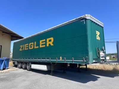 une semi-remorque verte garée devant un immeuble