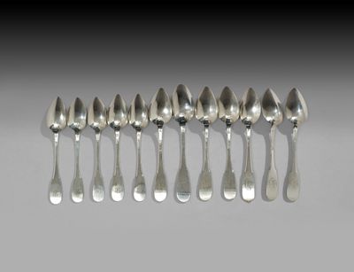 six cuillères en argent sont alignées sur une table