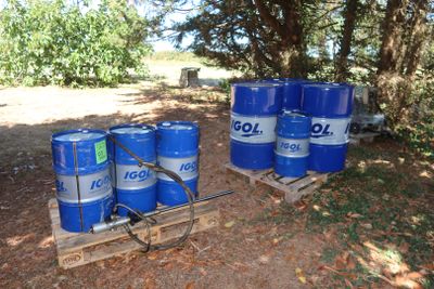 several blue barrels sitting on top of a wooden pallet next to a forest