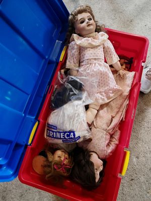 une poupée posée dans un bac en plastique, par terre