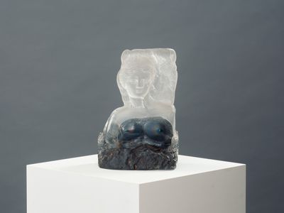 sculpture of a woman sitting on a rock on a white pedestal