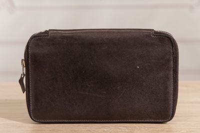 a brown toilet bag sitting on top of a wooden table