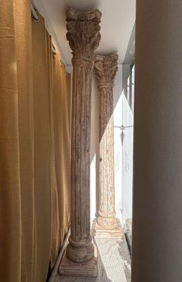 une grande colonne au milieu d'un couloir orné de rideaux