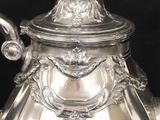 a silver tea pot with a lid on a black background