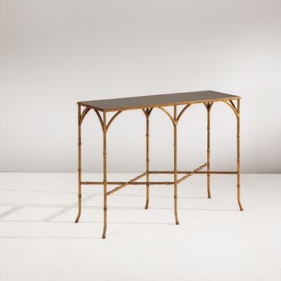 une console en bambou doré avec un plateau noir